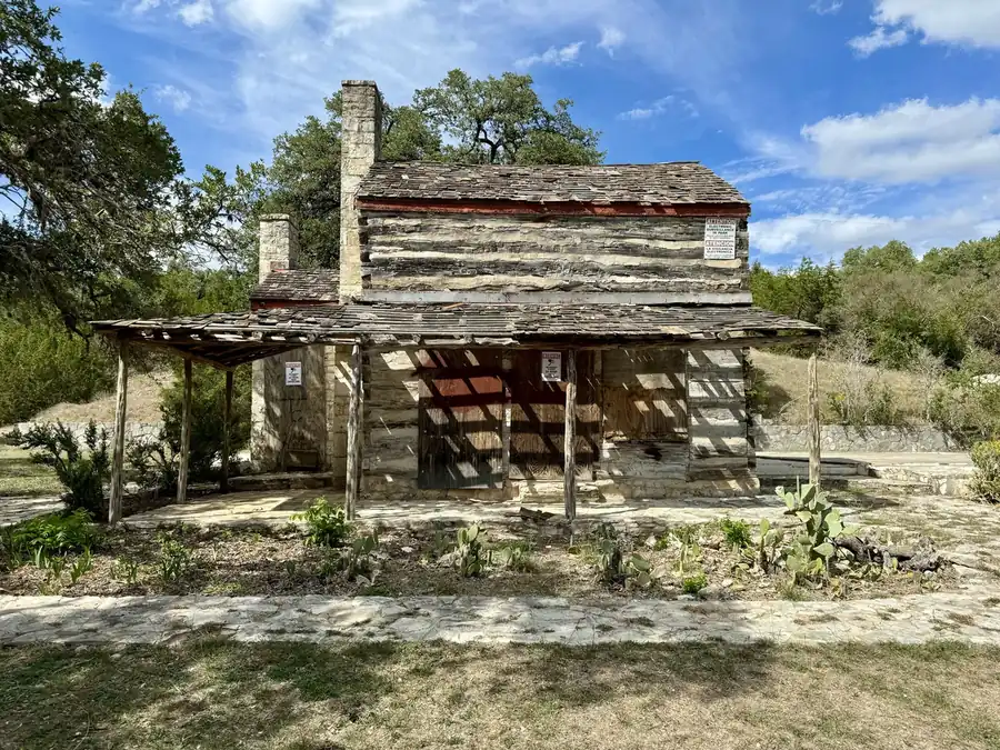 The John M. King Log House in Cedar Park with its limestone chimney and covered porch under oak trees