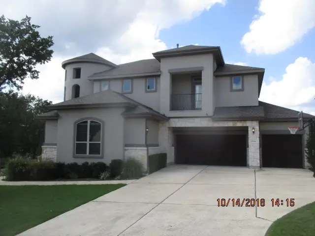 Finished gray roof on a two-story stucco and stone home with a turret