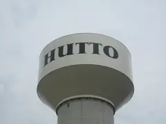 The Hutto water tower with HUTTO painted on the tank against a gray sky