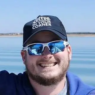 Jake, Frank's son, smiling in a navy cap and mirrored sunglasses on the lake