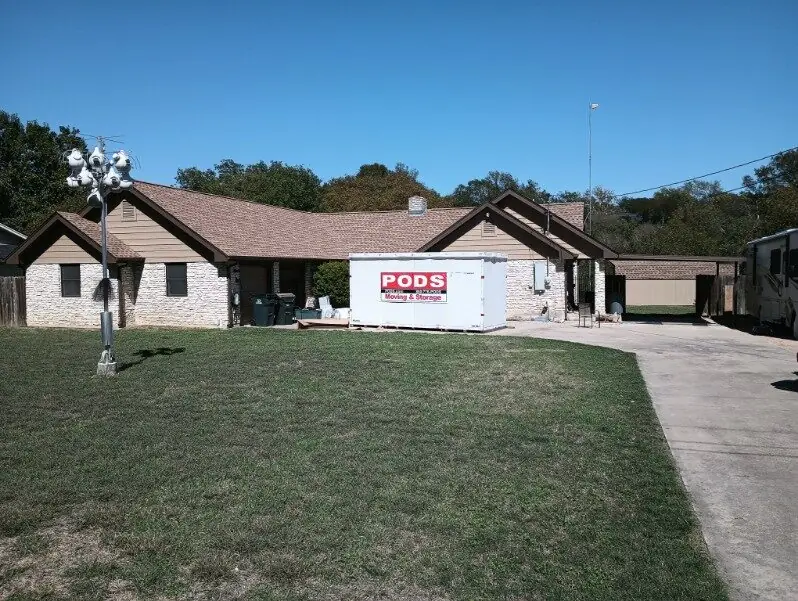 Front elevation of a stone ranch home during a re-roof with a container on site