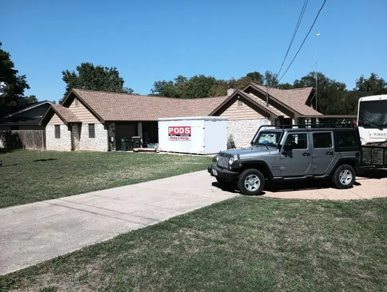 Ranch home mid re-roof with a storage container and a Jeep in the driveway